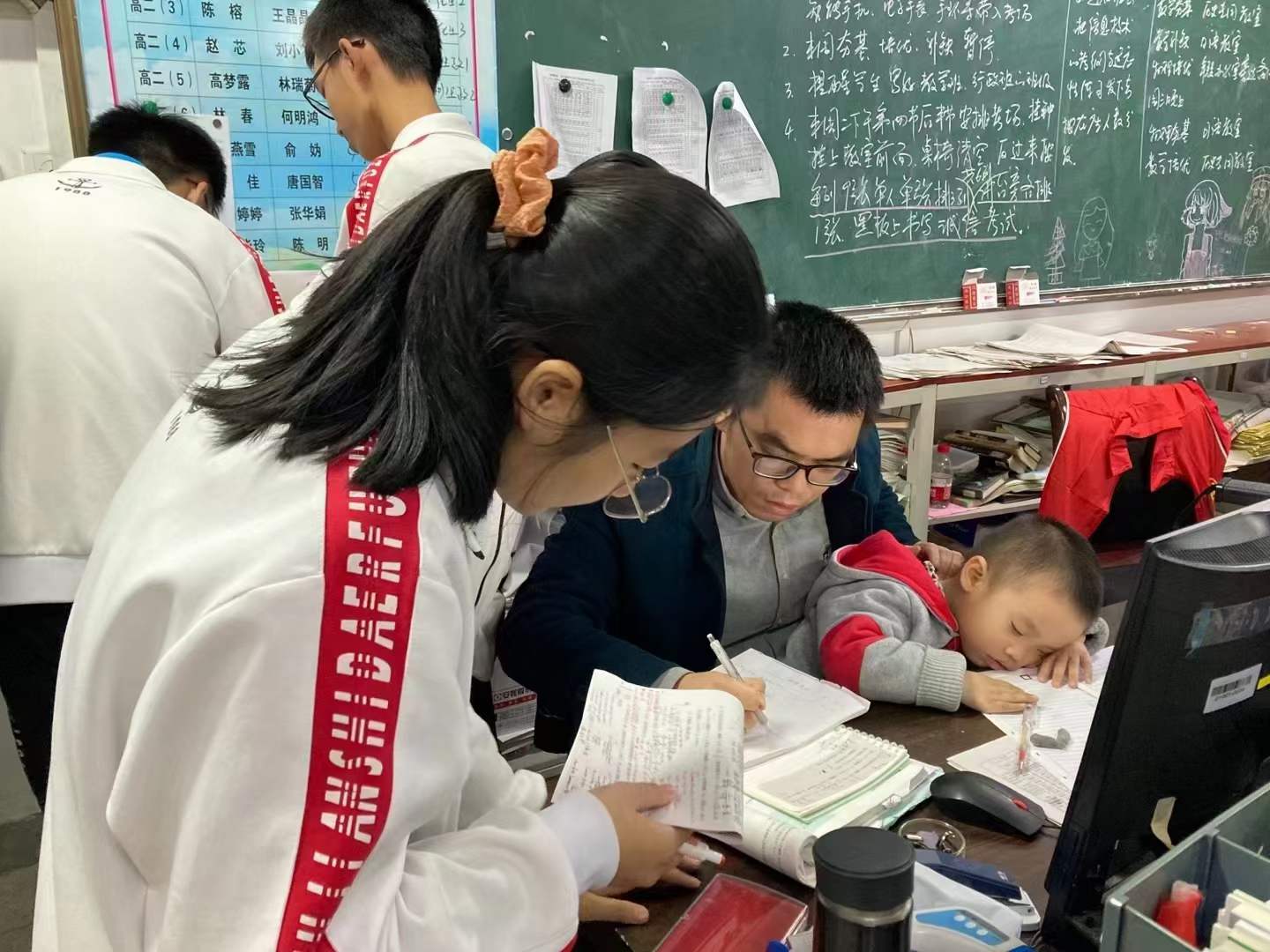 他在给学生讲题，年幼的孩子却睡在了他的怀里